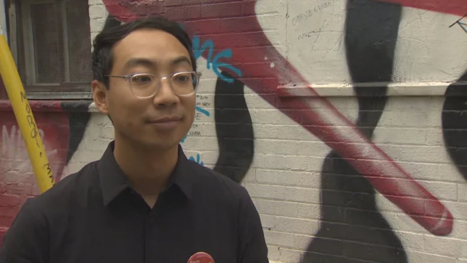 A man in front of a brick wall and graffiti.